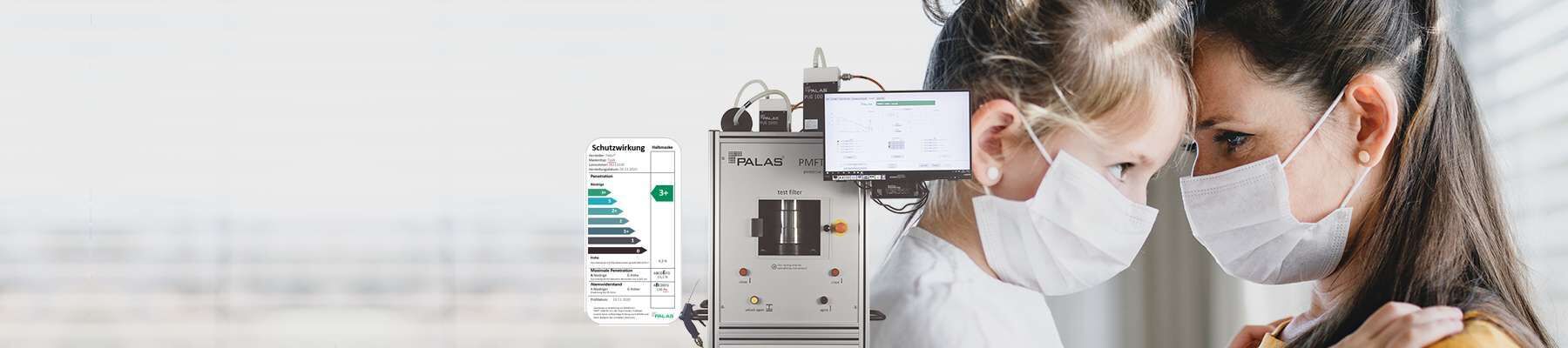 filterpr&uuml;fstand-pmft-neben-frau-und-kind-mit-schutzmaske