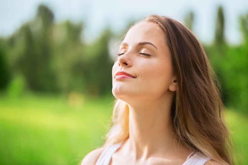 Serenity in Nature: Woman Standing in Green Field, Basking in Sunlight and Clean Air