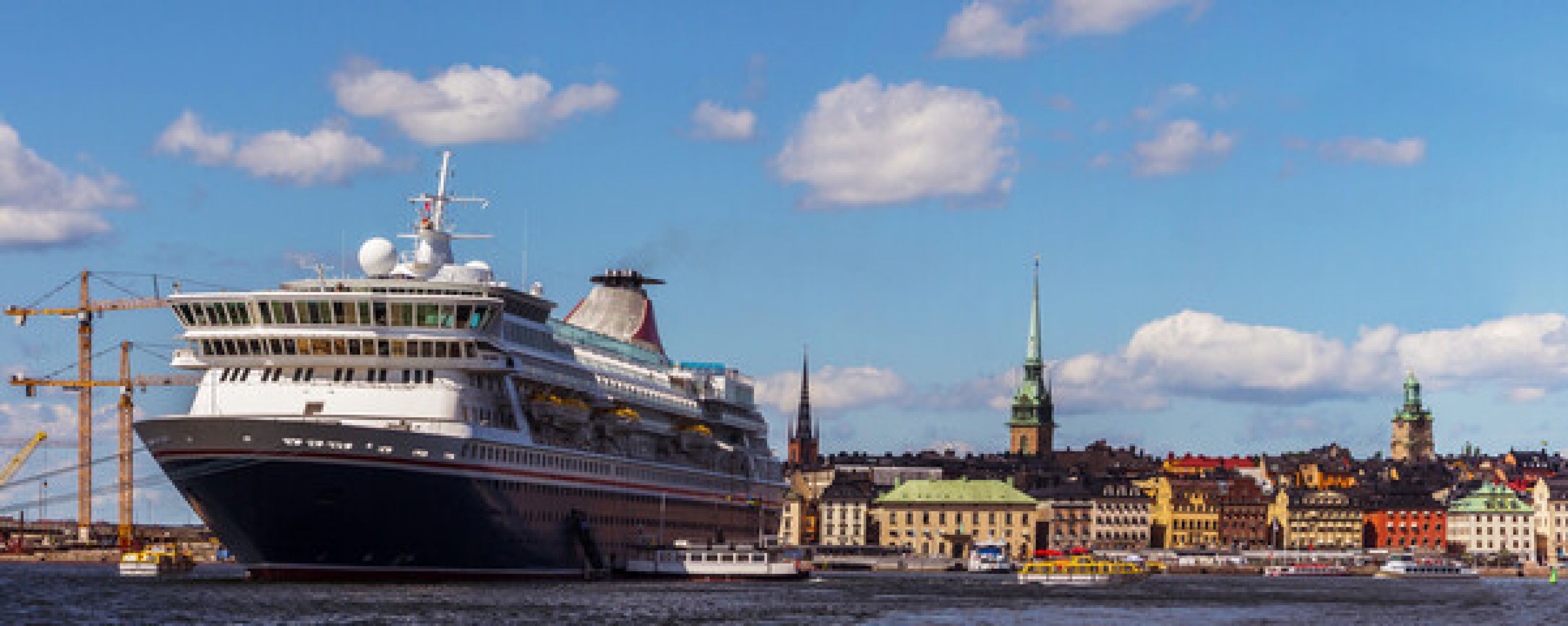 Striking image of a large anchoring ship in the harbor of a European city, showcasing the city skyline. Palas plays a role in monitoring emissions at harbors to contribute to an environment friendly behavior.