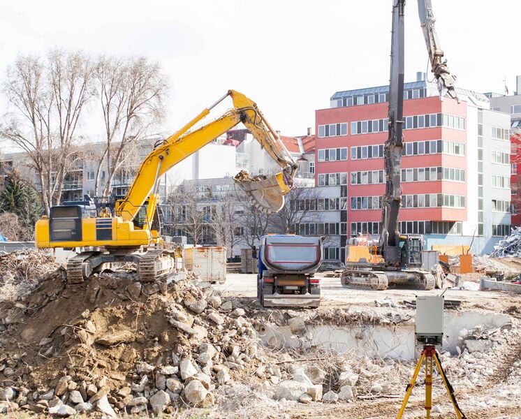 An excavator on an urban construction site in Germany, using Palas®' rental service for air quality monitoring devices.