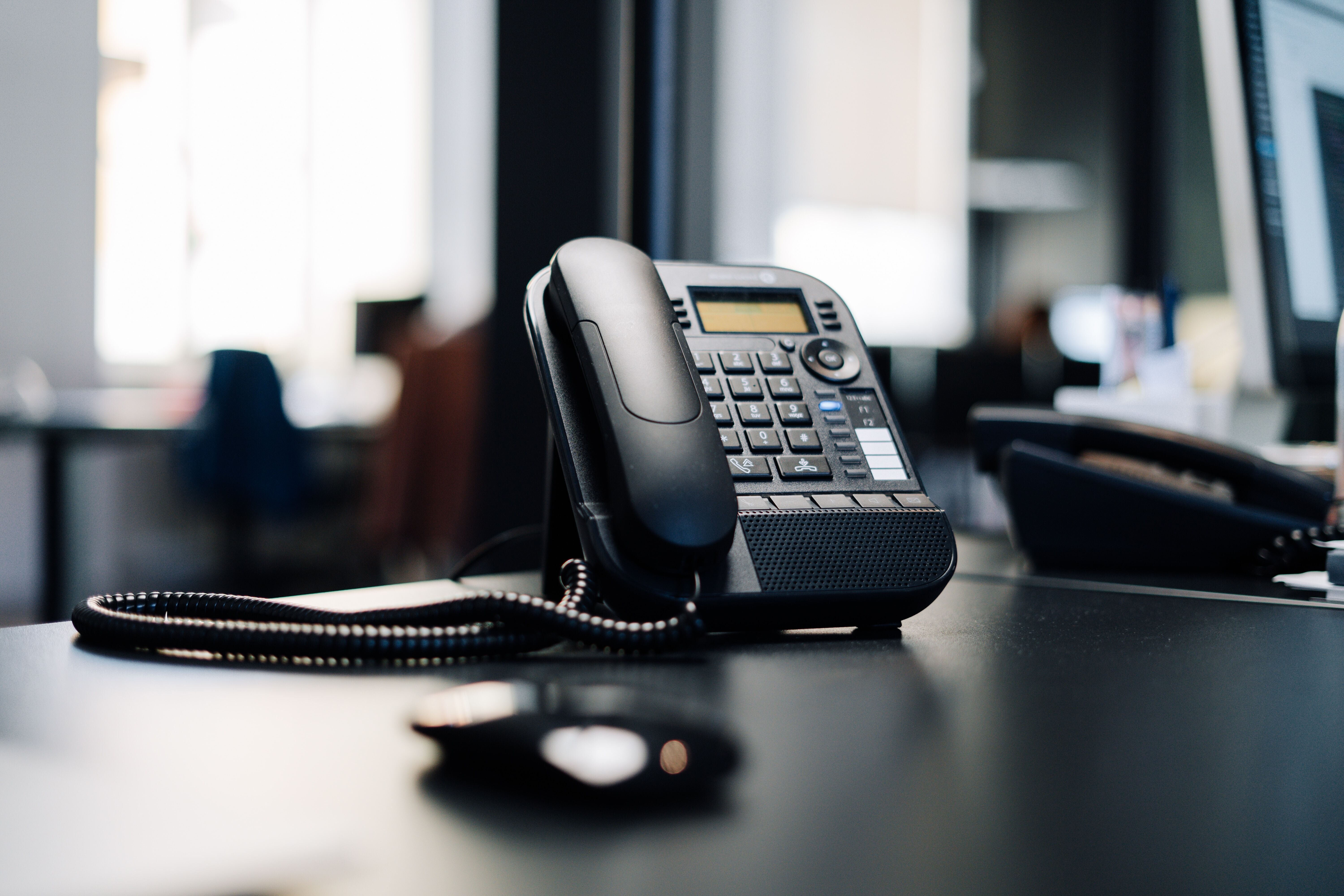 A telephone placed on a desk, facilitating communication in the workspace