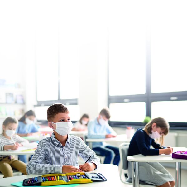 Young students wearing masks as a safety measure, sitting attentively in a classroom setting. Notably, Palas offers various devices contributing to virus protection in different environments.