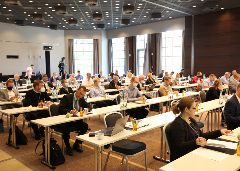 gesch&auml;ftsleute-sitzen-in-kongressraum-an-tischen