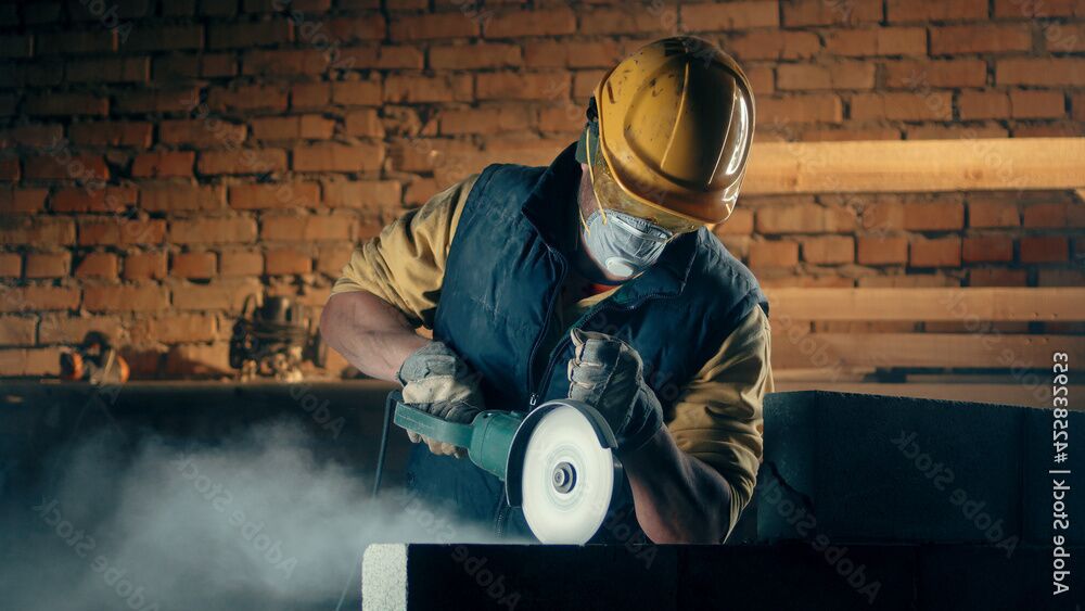 Skilled worker wearing helmet and protective mask operating a saw with precision