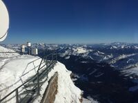 Scenic view from Sonnblick Observatory, featuring Palas-installed air quality monitoring devices. The observatory overlooks the majestic Alps, showcasing snow-covered mountains and a picturesque valley.
