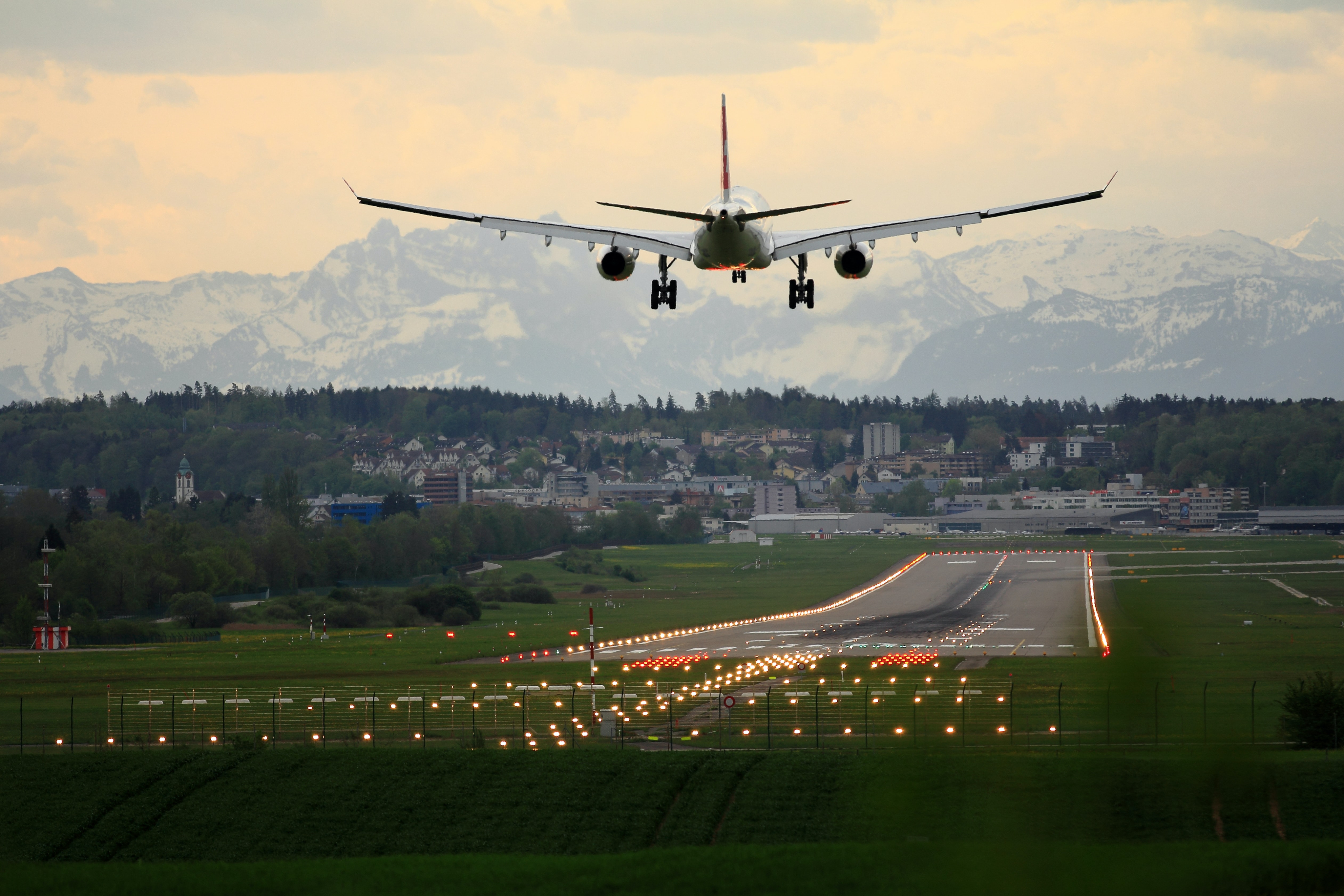 A captivating scene capturing a plane descending on a runway against the backdrop of snow-covered mountains. Palas contributes to controlling aerosols caused by air traffic for a cleaner environment.