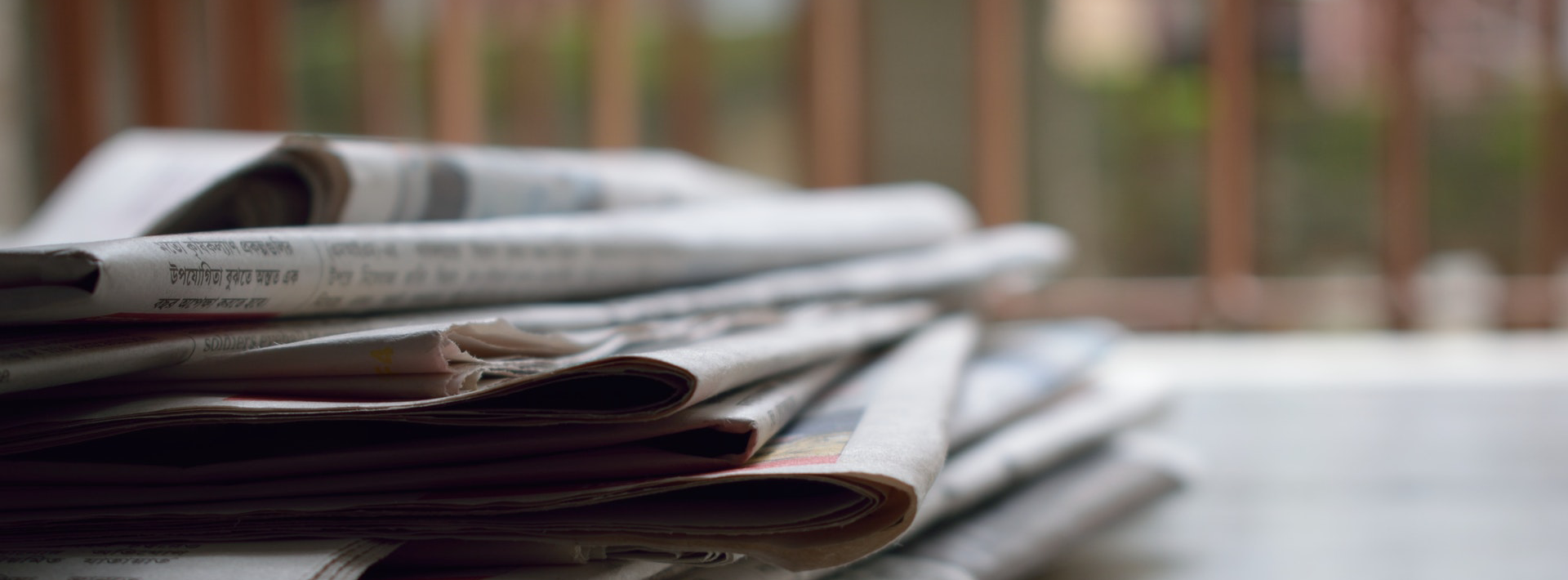 A stack of newspapers on a table, highlighting that the latest news about Palas can be found on the company's website, providing updates and insights.