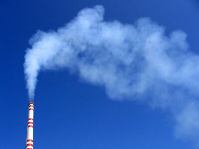 Industrial Emissions: Chimney Against Blue Sky Emitting Smoke
