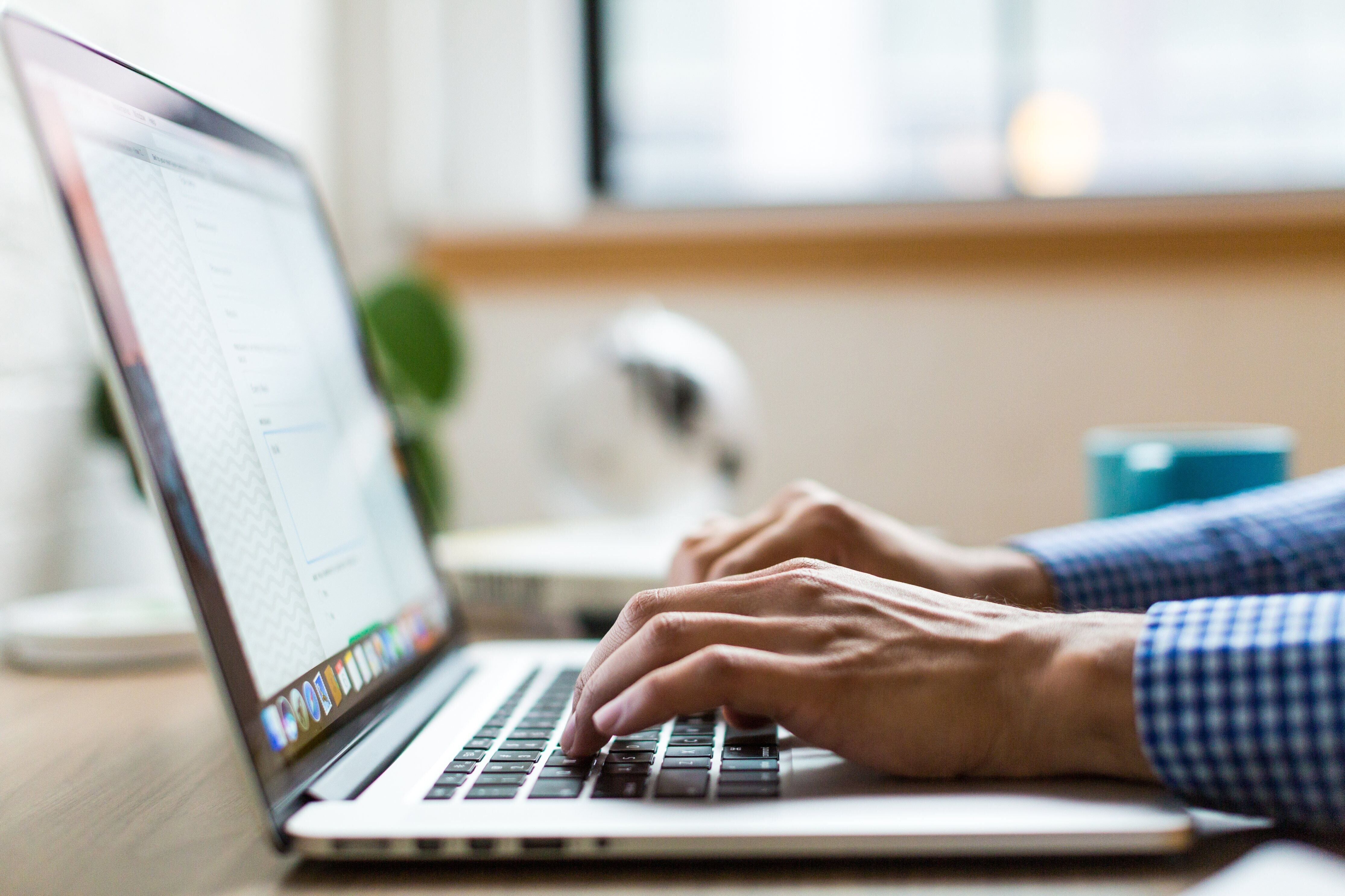 A focused man typing on a laptop, showcasing productivity in a modern workspace